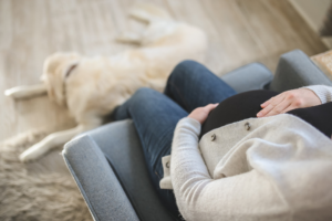 mujer embarazada sentada en el sofá junto a su perro